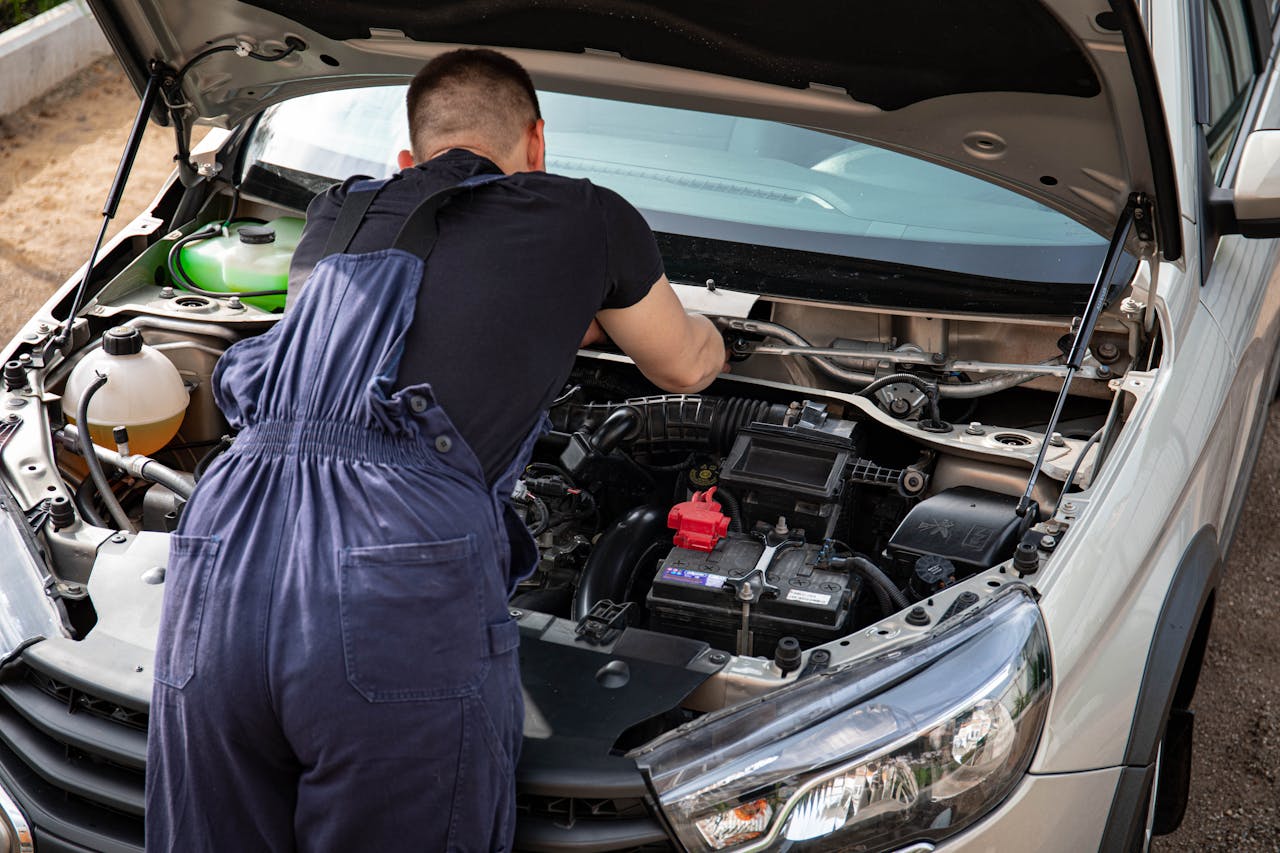Close-up of mechanic repairing a car engine. Outdoor setting during the day.
